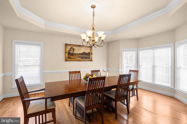 dining space with hardwood / wood-style flooring, ornamental molding, a tray ceiling, and an inviting chandelier