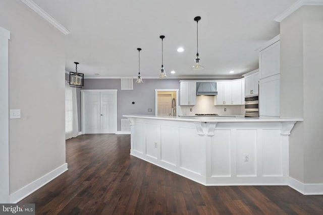 kitchen with dark hardwood / wood-style floors, decorative light fixtures, white cabinetry, backsplash, and custom exhaust hood