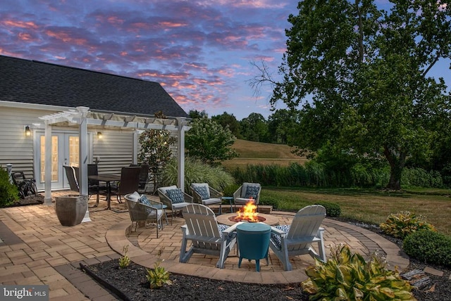 patio terrace at dusk featuring french doors, a pergola, and a fire pit