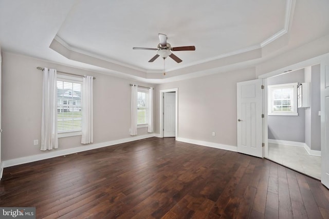 empty room with crown molding, dark wood-type flooring, ceiling fan, and a tray ceiling