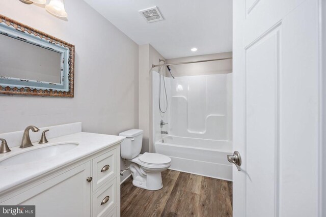 full bathroom with hardwood / wood-style flooring, vanity, shower / washtub combination, and toilet