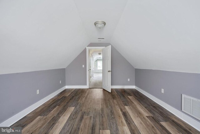 additional living space with vaulted ceiling and dark hardwood / wood-style floors