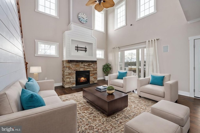 living room with wood-type flooring, a stone fireplace, a healthy amount of sunlight, and ceiling fan