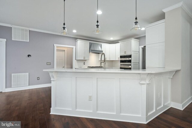 kitchen with hanging light fixtures, white cabinetry, premium range hood, and ornamental molding