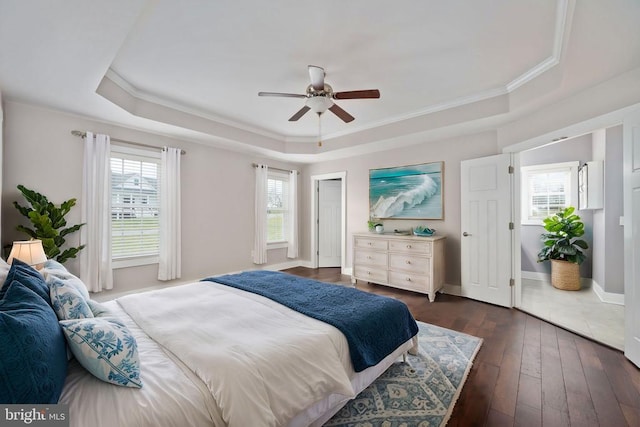 bedroom featuring dark hardwood / wood-style flooring, a tray ceiling, crown molding, and ceiling fan