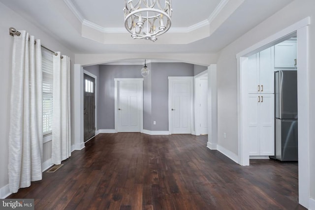 interior space featuring crown molding, dark hardwood / wood-style floors, a raised ceiling, and a notable chandelier