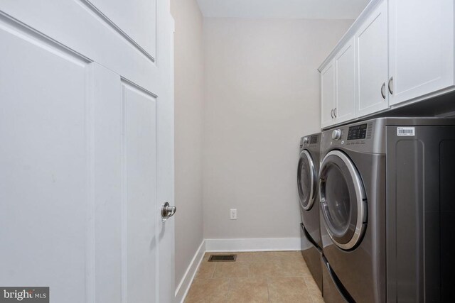 laundry room featuring cabinets, washing machine and clothes dryer, and light tile patterned flooring