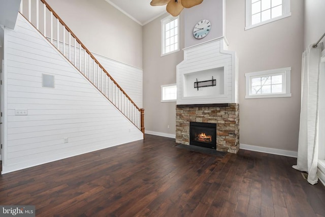 unfurnished living room with a fireplace, a towering ceiling, dark wood-type flooring, and ornamental molding