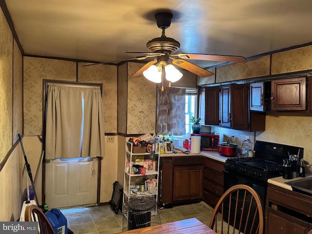 13093 Stonehouse Mountain Rd, Culpeper, VA 22701 - kitchen with black gas stove, ceiling fan, wallpapered walls, light countertops, and dark brown cabinets