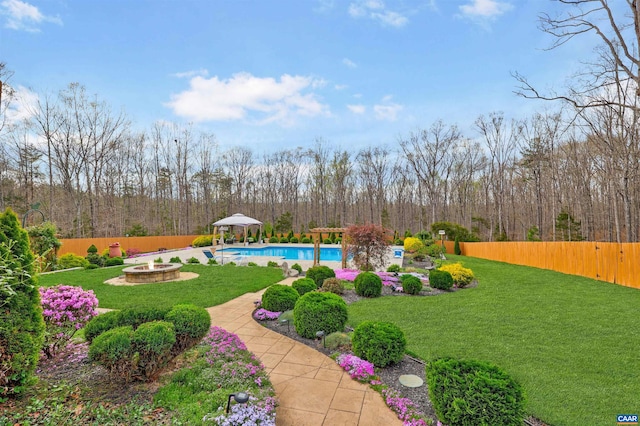 view of yard with a fenced in pool, a view of trees, an outdoor fire pit, a gazebo, and a fenced backyard