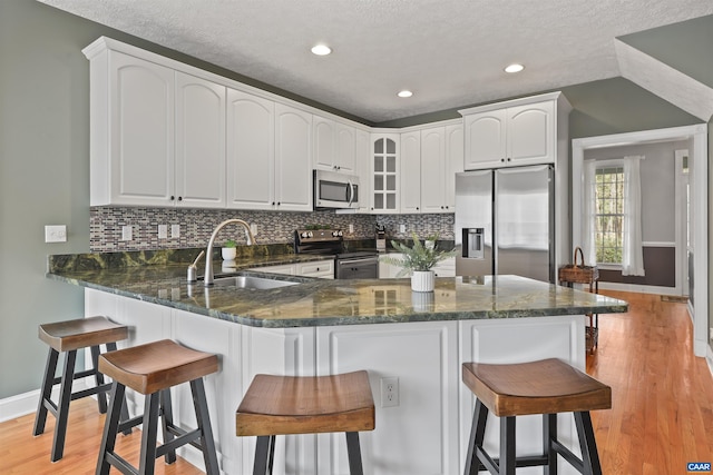 kitchen with baseboards, stainless steel appliances, a peninsula, and a sink