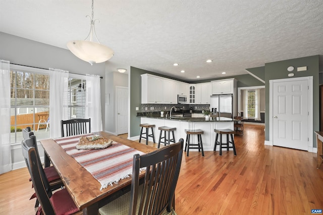 dining room with baseboards, recessed lighting, light wood-type flooring, and a textured ceiling