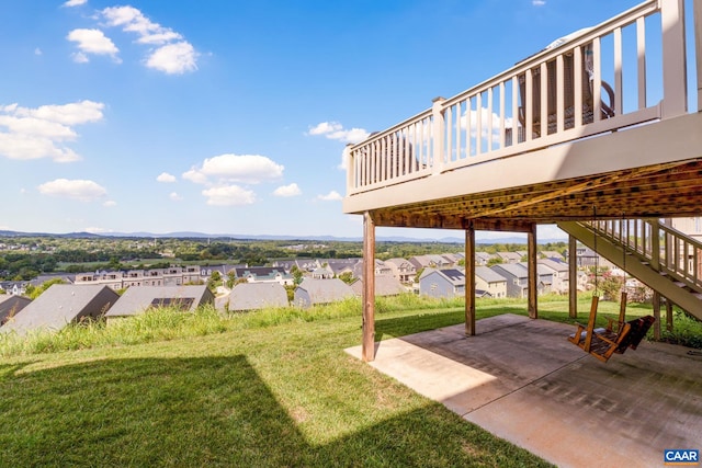 view of green lawn featuring a residential view, a patio, a wooden deck, and stairway