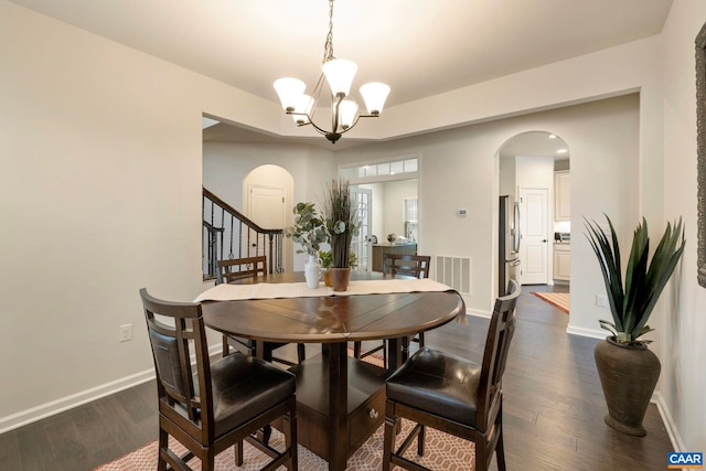 dining space with arched walkways, dark wood-style floors, a chandelier, and baseboards