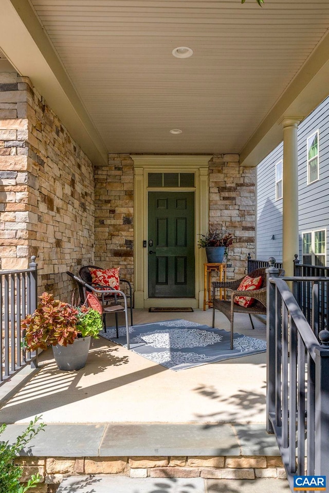 entrance to property with stone siding and a porch