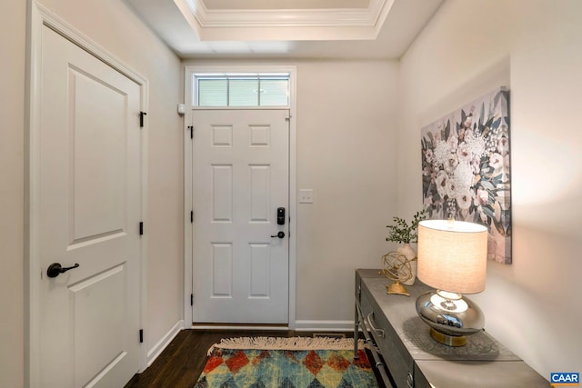 entryway featuring ornamental molding, dark wood-style floors, a raised ceiling, and baseboards