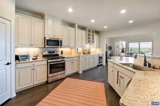 kitchen with appliances with stainless steel finishes, beverage cooler, a sink, tasteful backsplash, and recessed lighting