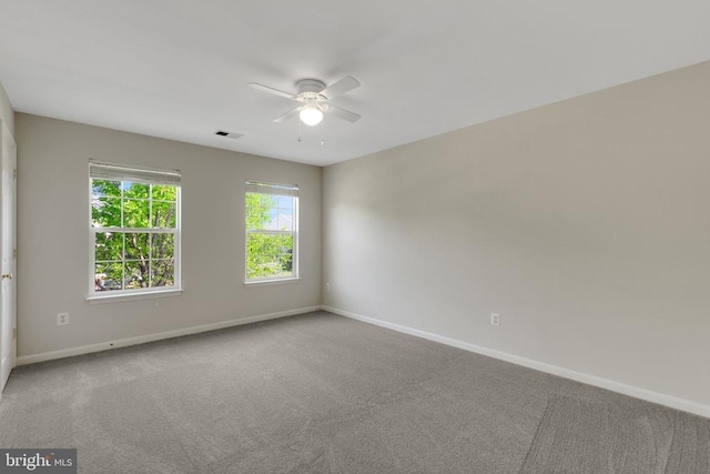 carpeted spare room featuring ceiling fan, baseboards, and visible vents