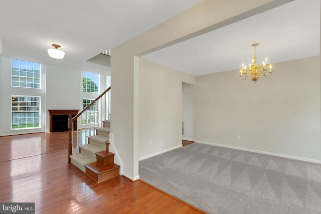 interior space featuring a notable chandelier, baseboards, wood finished floors, stairway, and a fireplace