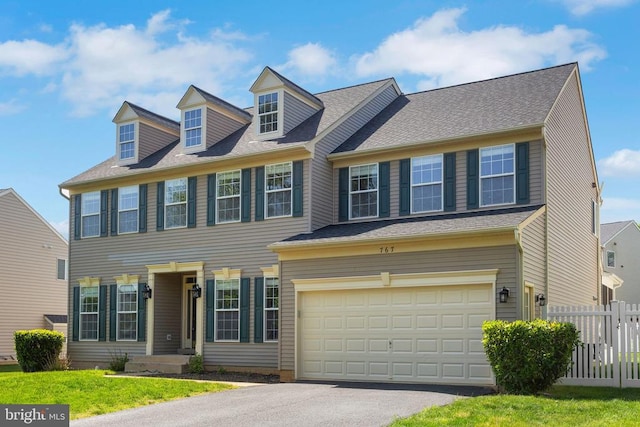 colonial home featuring driveway, an attached garage, and fence