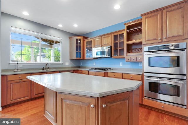 kitchen with light wood-style floors, light countertops, appliances with stainless steel finishes, and a sink