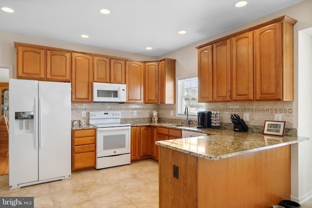 kitchen featuring brown cabinetry, white appliances, light stone counters, and a peninsula