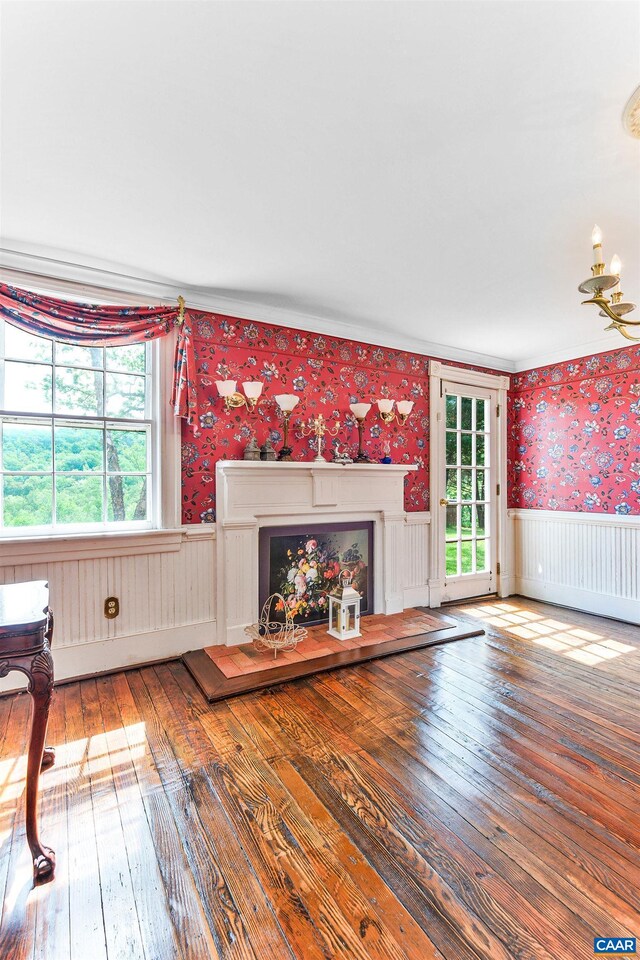 5722 James River Rd, Gladstone, VA 24553 - unfurnished living room with wallpapered walls, a wainscoted wall, a fireplace with raised hearth, wood-type flooring, and healthy amount of natural light