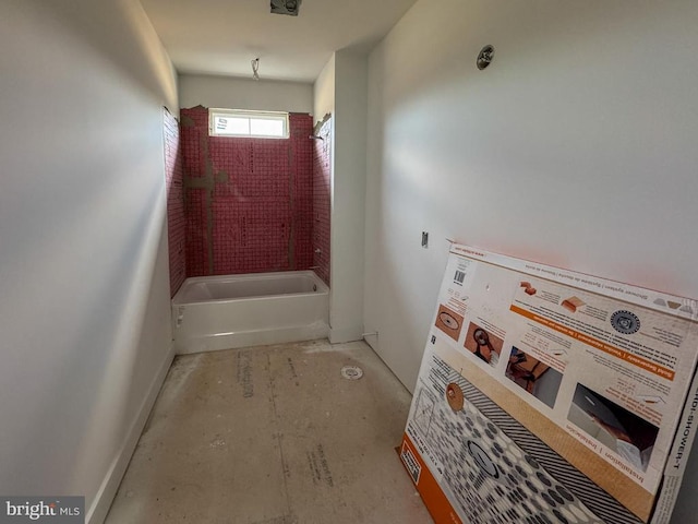 doorway featuring baseboards and concrete flooring