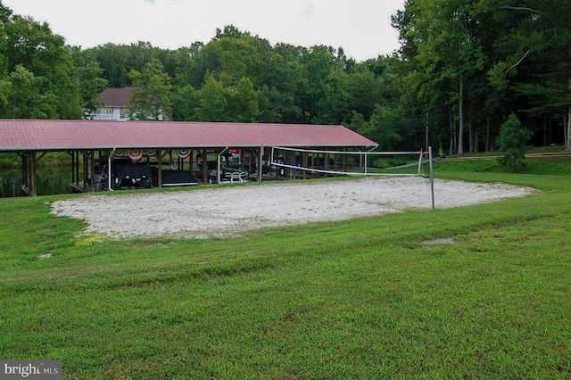 view of property's community featuring volleyball court, a yard, and a wooded view
