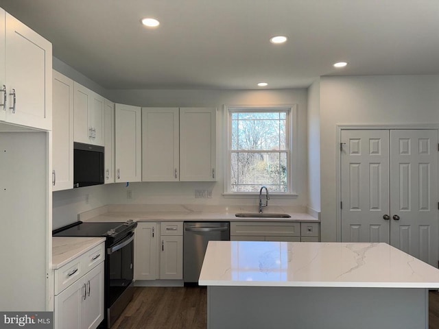 kitchen featuring black appliances, a sink, light stone counters, dark wood-type flooring, and white cabinetry
