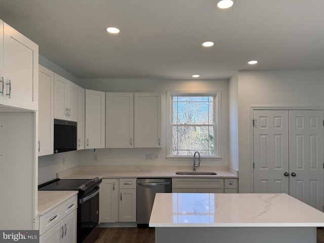 kitchen with black appliances, a sink, light stone countertops, recessed lighting, and white cabinets