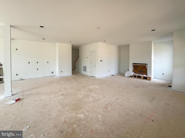 unfurnished living room featuring stairway
