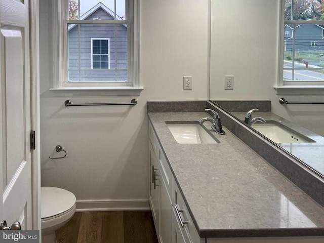 bathroom with baseboards, wood finished floors, vanity, and toilet