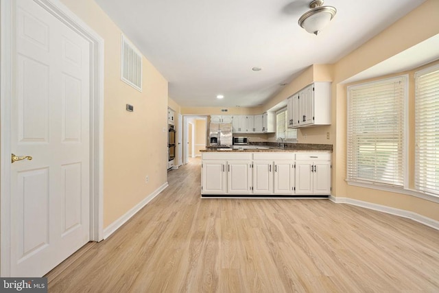6904 Lakeland Way, Fredericksburg, VA 22407 - kitchen with appliances with stainless steel finishes, light wood-type flooring, white cabinets, dark countertops, and a peninsula