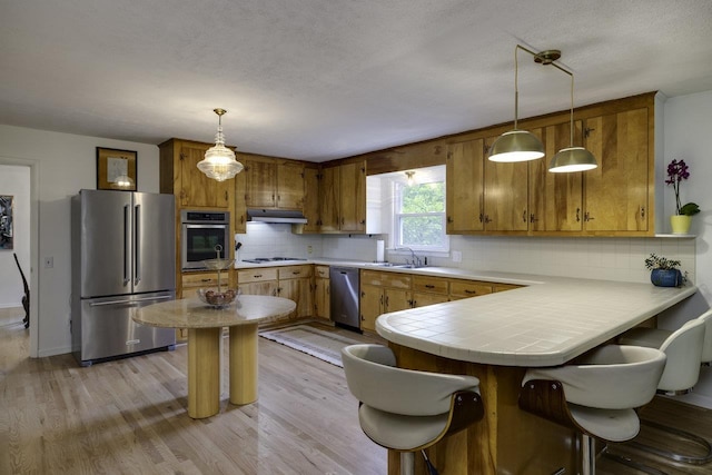 1217 Windsor Rd, Harrisonburg, VA 22801 - kitchen with a sink, a peninsula, brown cabinets, under cabinet range hood, and appliances with stainless steel finishes