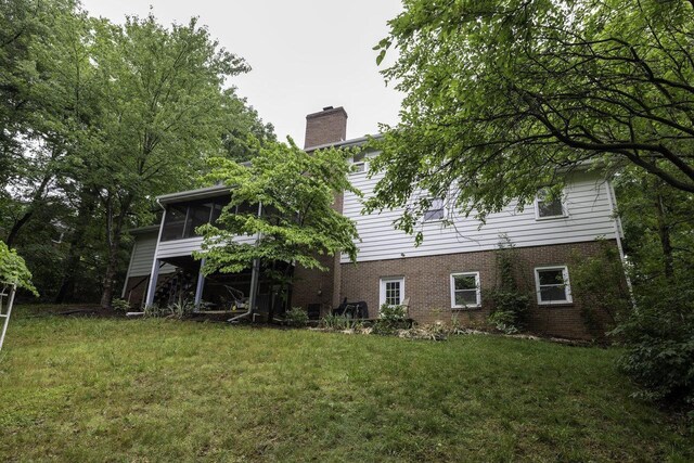 1217 Windsor Rd, Harrisonburg, VA 22801 - rear view of house featuring a sunroom, brick siding, a chimney, and a lawn