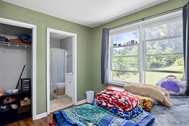 872 Camelot Ln, Harrisonburg, VA 22801 - bedroom featuring multiple windows, wood finished floors, a closet, a textured ceiling, and ensuite bathroom