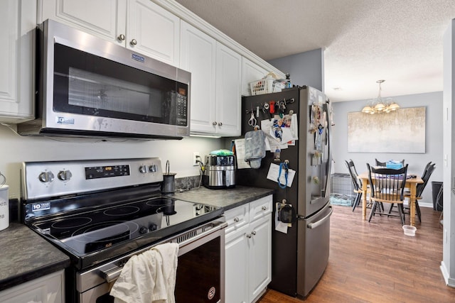 872 Camelot Ln, Harrisonburg, VA 22801 - kitchen with stainless steel appliances, dark countertops, a chandelier, white cabinetry, and wood finished floors
