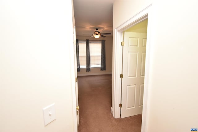 corridor featuring baseboards and carpet floors