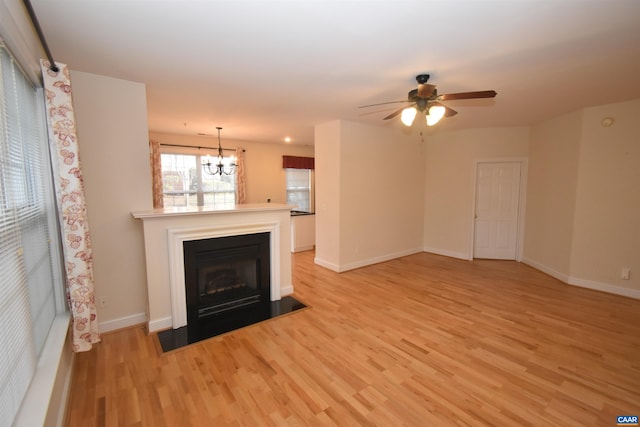 unfurnished living room with baseboards, a fireplace with flush hearth, light wood-type flooring, and ceiling fan with notable chandelier