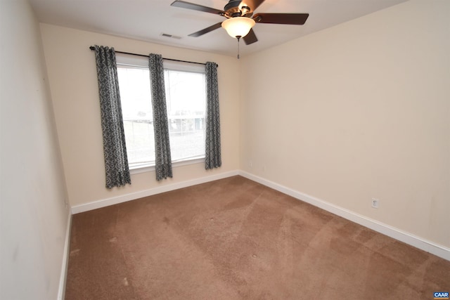 carpeted spare room with baseboards, ceiling fan, and visible vents
