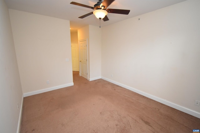 spare room with light colored carpet, baseboards, and ceiling fan