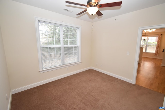 carpeted empty room with ceiling fan with notable chandelier, baseboards, and visible vents