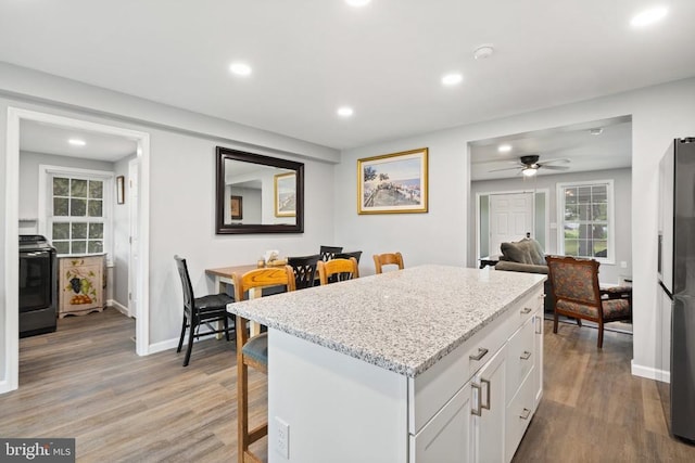 8558 Opal Rd, Warrenton, VA 20186 - kitchen with stove, a kitchen bar, light wood-style flooring, white cabinets, and recessed lighting