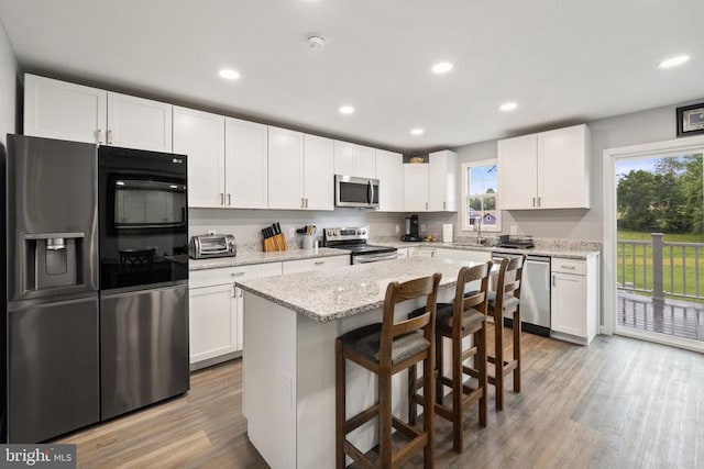 8558 Opal Rd, Warrenton, VA 20186 - kitchen with stainless steel appliances, white cabinets, light wood-type flooring, a breakfast bar area, and recessed lighting