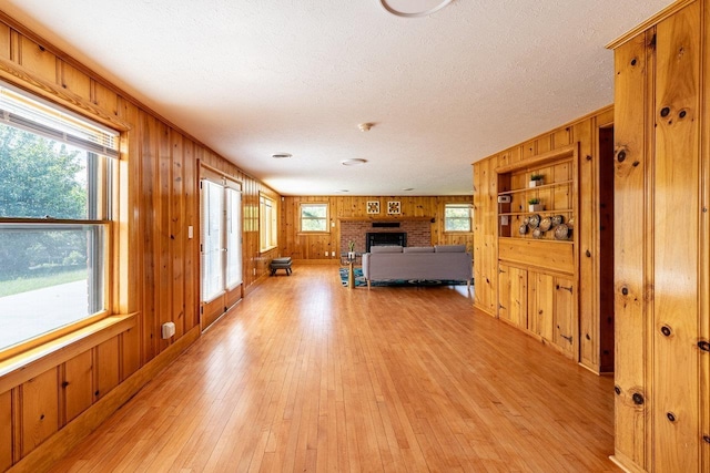 10999 Orkney Grade, Mount Jackson, VA 22842 - unfurnished bedroom featuring wooden walls, light wood finished floors, a fireplace, and a textured ceiling