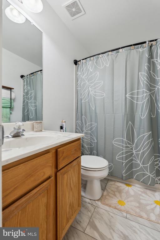 full bathroom with visible vents, vanity, marble finish floor, toilet, and lofted ceiling