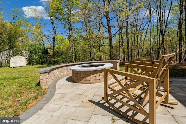 view of patio / terrace with an outdoor structure, an outdoor fire pit, and a shed