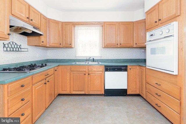 kitchen with a sink, light floors, white appliances, and under cabinet range hood