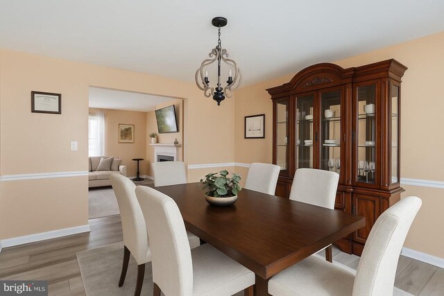 12107 Knight Ct, Fredericksburg, VA 22407 - dining area featuring a chandelier, light wood-type flooring, baseboards, and a fireplace